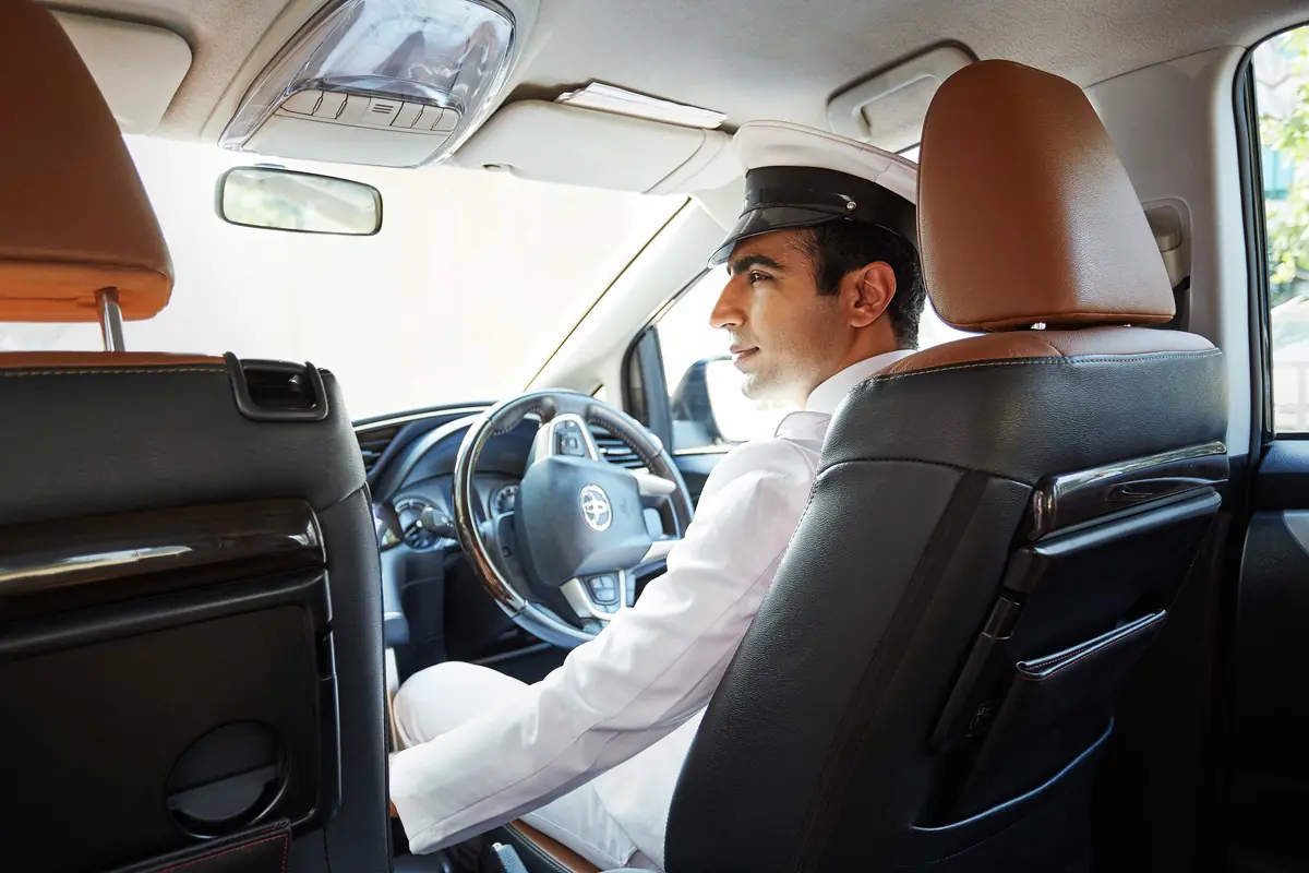 A uniformed PickDrop.PK driver at the wheel of a car